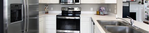 Luxury apartments with spacious u-shaped kitchen, white cabinets, stainless steel appliances, bright white kitchen at Rockledge Oaks Apartments in Lincoln, Nebraska