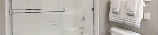 Luxury bathroom with tiled floors, glass shower, and oval soaking tub at Rockledge Oaks Apartments in Lincoln, Nebraska
