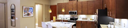 Luxury apartments with spacious kitchen and built-in wine rack, granite countertops, kitchen island, stainless steel appliances, and designer tile backsplash at Tuscany Walk Apartments in Houston Texas.