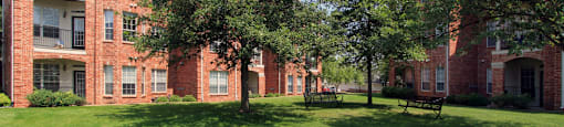 Luxury apartments with red brick exterior, lush landscaping, park-like setting, and scenic views at Lenox Village Apartments in Lincoln, Nebraska