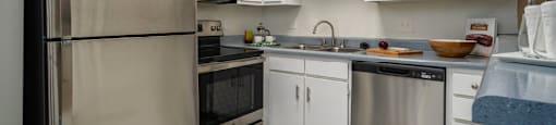 Kitchen with white cabinets, stainless steel appliances, and breakfast bar at Woodlake on the Bayou Apartments