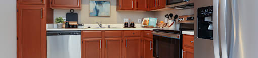 Spacious kitchen with stainless steel appliances, side-by-side refrigerator with water dispenser, recessed ceiling, and lots of cabinet space at The Dorchester Apartments in Dallas Texas