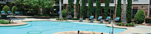 Luxury swimming pool with cabanas, poolside lounges, grilling stations, palm trees and beautiful landscaping at The Voss Apartments in Houston.