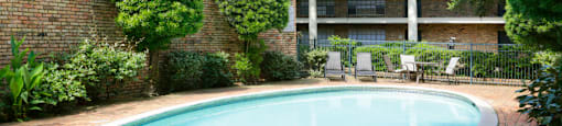 Apartments near the Galleria with multiple swimming pools, sun deck with poolside lounge chairs, brick exteriors and courtyard setting at Plantation apartments in Houston.