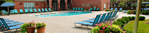 Luxury apartments with swimming pool, poolside lounge chairs, picnic area, grilling station, lush landscaping, and scenic views at Lenox Village Apartments in Lincoln, Nebraska
