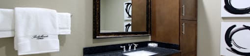Luxury bathroom with oval soaking tub, glass shower, granite countertops and linen closet at Bellemeade Apartments in west Des Moines