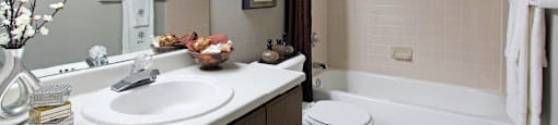 Spacious bathroom with lots of cabinet space, tiled floor, tiled shower, extra cabinet space, and gray wall color at The Vanderbilt Apartments in Omaha, Nebraska