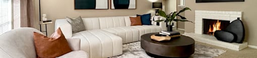 Spacious living room with oversized windows, lots of natural light, and woodburning fireplace at Woodlake Oaks Apartments in Houston.