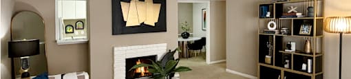 Spacious living room with oversized windows, lots of natural light, and woodburning fireplace at Woodlake Oaks Apartments in Houston.
