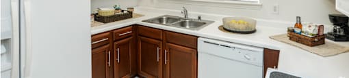 Spacious kitchen with honey brown toned cabinets with modern silver hardware, and white appliances including a double sided fridge with water and ice dispenser.