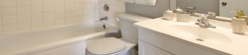 Bathroom with white cabinets, tiled floor, tiled shower with tub, and gray wall color at The Inverness Apartments in La Vista, Nebraska