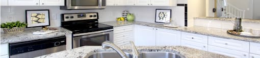 Spacious kitchen with island, granite countertops, white cabinets, smooth glass top stove, spacious pantries, breakfast bar and stainless-steel appliances at Tuscany Villas in Houston.