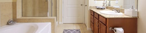 Spacious master bathroom with oval soaking tub, separate glass shower, and spacious linen closet at The Voss Apartments in Houston.