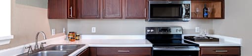 Spacious kitchen with stainless steel appliances and plank wood floors at Village on the Parkway Apartments