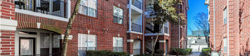 Luxury apartments with brick exteriors, beautiful landscaping, and patios with extra storage and French doors at Tuscany Apartments in Houston.