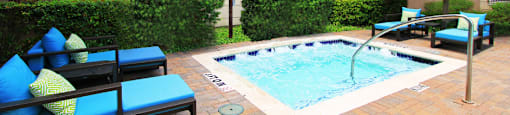 Luxury apartments with palm trees, spa, hot tub, spacious sundeck with poolside lounge chairs, beautiful landscaping, and fountains at Villa Piana Apartments in Dallas