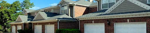 Luxury apartments in a gated community with red brick exteriors and attached garages at Prestonbridge Apartments in North Dallas