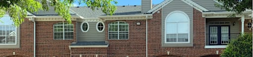 Luxury apartments in a gated community with red brick exteriors and attached garages at Prestonbridge Apartments in North Dallas