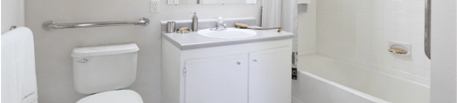 Spacious bathroom with white cabinets, linen closet, extra cabinet space, soaking tub and tiled shower at Breckenridge Apartments in Omaha, Nebraska