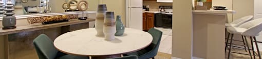 Dining room with mirror accent wall and U-shaped kitchen with breakfast bar at The Dorchester Apartments in north Dallas.