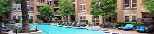 Luxury apartments with resort-style pool, palm trees, spacious sundeck with poolside lounge chairs, grilling station, fountains, and fitness center at Villa Piana Apartments in Dallas