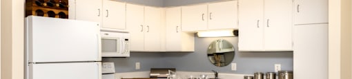 Kitchen with white cabinets, lots of cabinet space, kitchen island, prep island, and colored feature wall at Embassy Park Apartments in Omaha, Nebraska