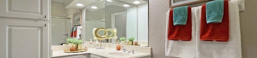 Luxury apartments with wood grain plank floors, extra cabinet space, white cabinets, built-in vanity, and glass shower at Lenox Village Apartments in Lincoln, NE