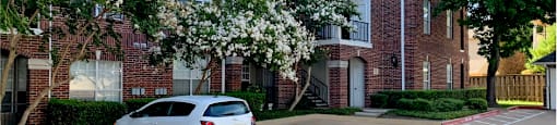 Luxury apartments in a gated community with red brick exteriors and beautiful landscaping at Prestonbridge Apartments in North Dallas