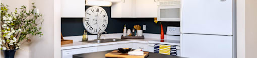 Kitchen with white cabinets, lots of cabinet space, kitchen island, prep island, and colored feature wall at Embassy Park Apartments in Omaha, Nebraska