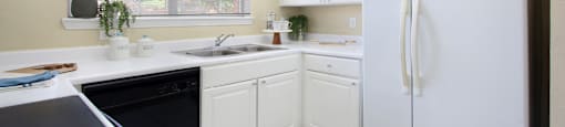 Spacious u-shaped kitchen, luxury apartments with bright white kitchen and side-by-side refrigerator at Saddlebrook apartments in Urbandale, Iowa