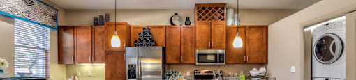 Luxury apartments next to the Galleria in Dallas with spacious floor plan, granite countertops, stainless steel appliances, built-in wine rack, kitchen island, front-loading washer and dryer and porcelain tile floor at Villa Piana Apartments in Dallas