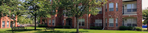 Luxury apartments with red brick exterior, spacious balconies, lush landscaping, park-like setting, and scenic views at Lenox Village Apartments in Lincoln, Nebraska