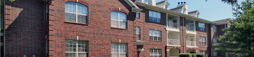 Luxury apartments with red brick exteriors, attached garages, spacious balconies, lush landscaping, and scenic views at Saddlebrook apartments in Urbandale Iowa