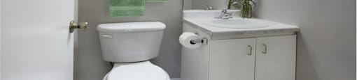 Half bath with white cabinets, tiled floor, and gray wall color at Inwood Apartments in La Vista, Nebraska