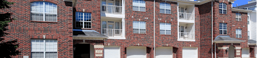 Luxury apartments with red brick exteriors, attached garages, spacious balconies, lush landscaping, and scenic views at Saddlebrook apartments in Urbandale Iowa