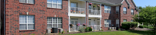 Luxury apartments with red brick exteriors, spacious balconies, lush landscaping, and scenic views at Saddlebrook apartments in Urbandale Iowa