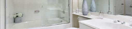 Luxury bathroom with tiled floors, oval soaking tub, built-in vanity, cultured marble vanity, glass shower and white cabinets in at TurtleCreek apartments in West Des Moines, Iowa