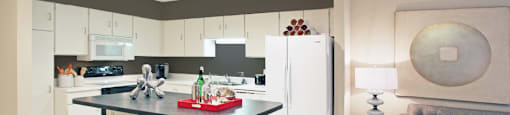 Large kitchen with lots of cabinet and counter space, white cabinets, colored feature wall, kitchen island, and prep island at Embassy Park Apartments in Omaha, Nebraska