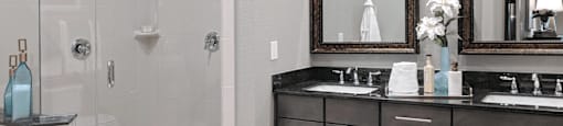 A double vanity bathroom with granite vanity top, a glass stand-in shower and a separate bathtub
