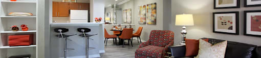 Luxury apartments with wood grain plank floors, dining room, u-shaped kitchen, mirror accent wall, built-in shelves, and breakfast bar at Lenox Village Apartments in Lincoln, Nebraska
