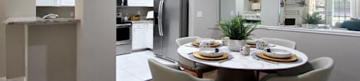Spacious dining room, mirror accent wall, white cabinets, u-shaped kitchen, stainless steel appliances, wood plank floor and side-by-side refrigerator at TurtleCreek apartments in West Des Moines, Iowa