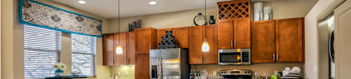 Luxury apartments with spacious kitchen with granite countertops, stainless steel appliances, built-in wine rack, kitchen island, and porcelain tile floor at Villa Piana Apartments in Dallas