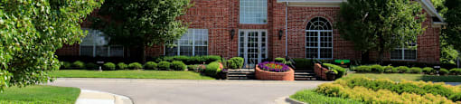 Luxury apartments with red brick exterior, lush landscaping, park-like setting, and scenic views at Lenox Village Apartments in Lincoln, Nebraska