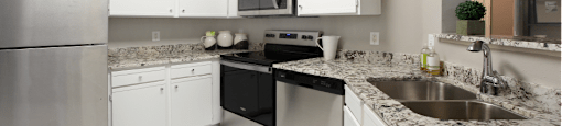 Spacious kitchen with white cabinets, granite countertops, stainless steel appliances, and porcelain tile floors at Breckenridge Apartments in southwest Omaha, Nebraska
