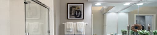 Luxury bathroom with tiled floors, oval soaking tub, built-in vanity, cultured marble vanity, glass shower and white cabinets in at TurtleCreek apartments in West Des Moines, Iowa