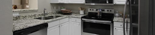 Luxury apartments with granite countertops, white cabinets, stainless steel appliances, and side-by-side refrigerator at TurtleCreek apartments in West Des Moines, Iowa