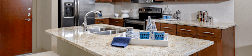 Luxury apartments in Bloomington Minnesota with granite countertops, stainless steel appliances, built-in wine rack, kitchen island, and porcelain tile floor at Luxembourg Apartments