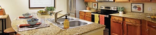 Luxury apartments with hardwood floors, granite countertops, side-by-side refrigerator, and stainless appliances at The Voss Apartments in Houston.