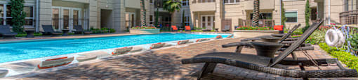 Luxury apartments with resort-style pool and palm trees, fountains, lap lane, and pool-side lounge chairs at Tuscany Walk Apartments in Houston