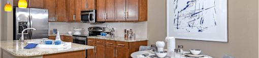 Luxury apartments in Bloomington Minnesota with granite countertops, stainless steel appliances, built-in wine rack, kitchen island, and porcelain tile floor at Luxembourg Apartments